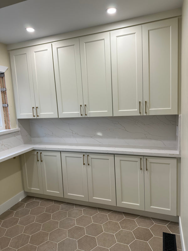 Modern kitchen with white cabinets, marble countertops, and hexagonal tile flooring.